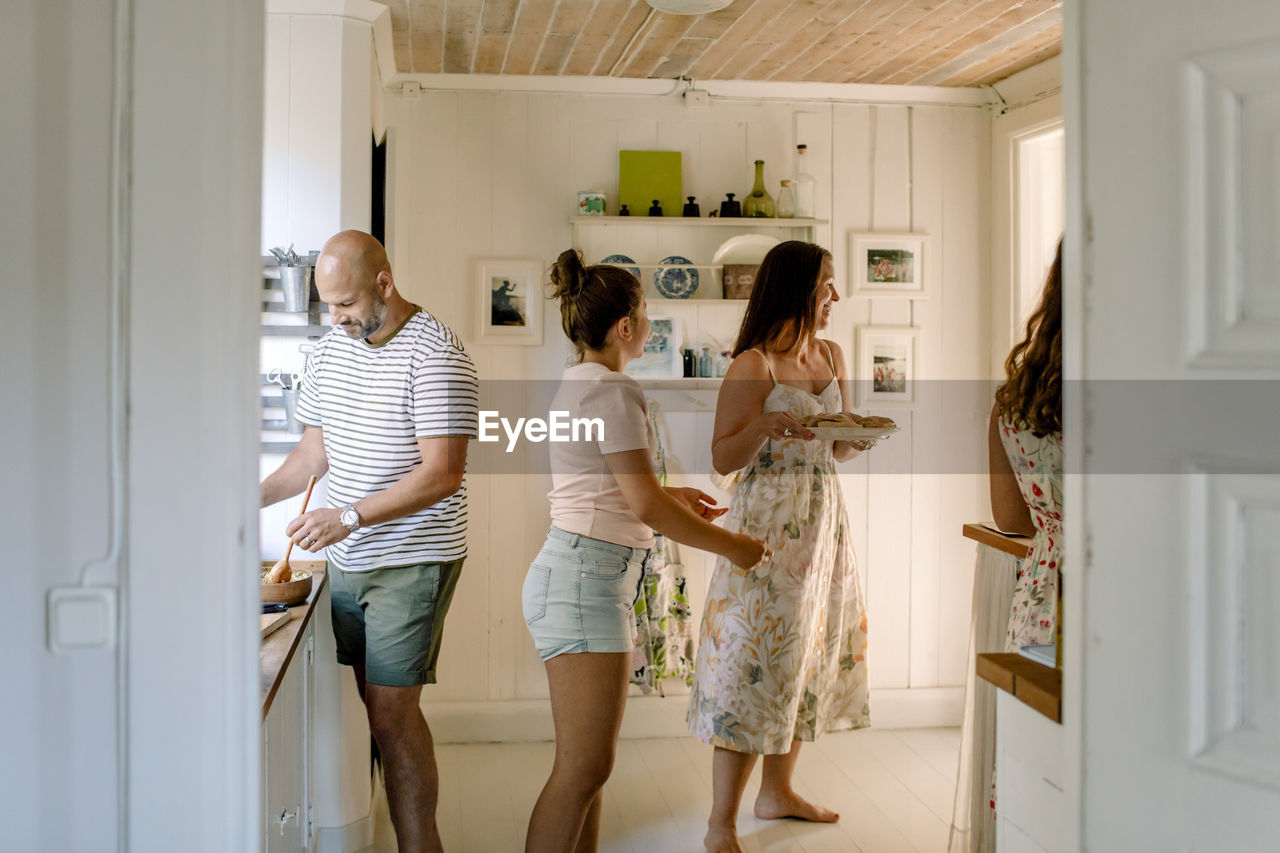 Smiling mother and daughters enjoying while preparing food in kitchen