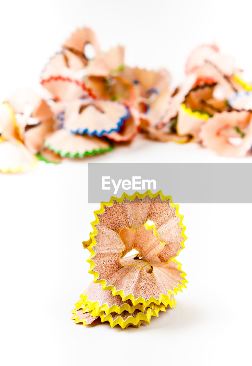 Yellow pencil shavings with more shavings at the background. vertical image.