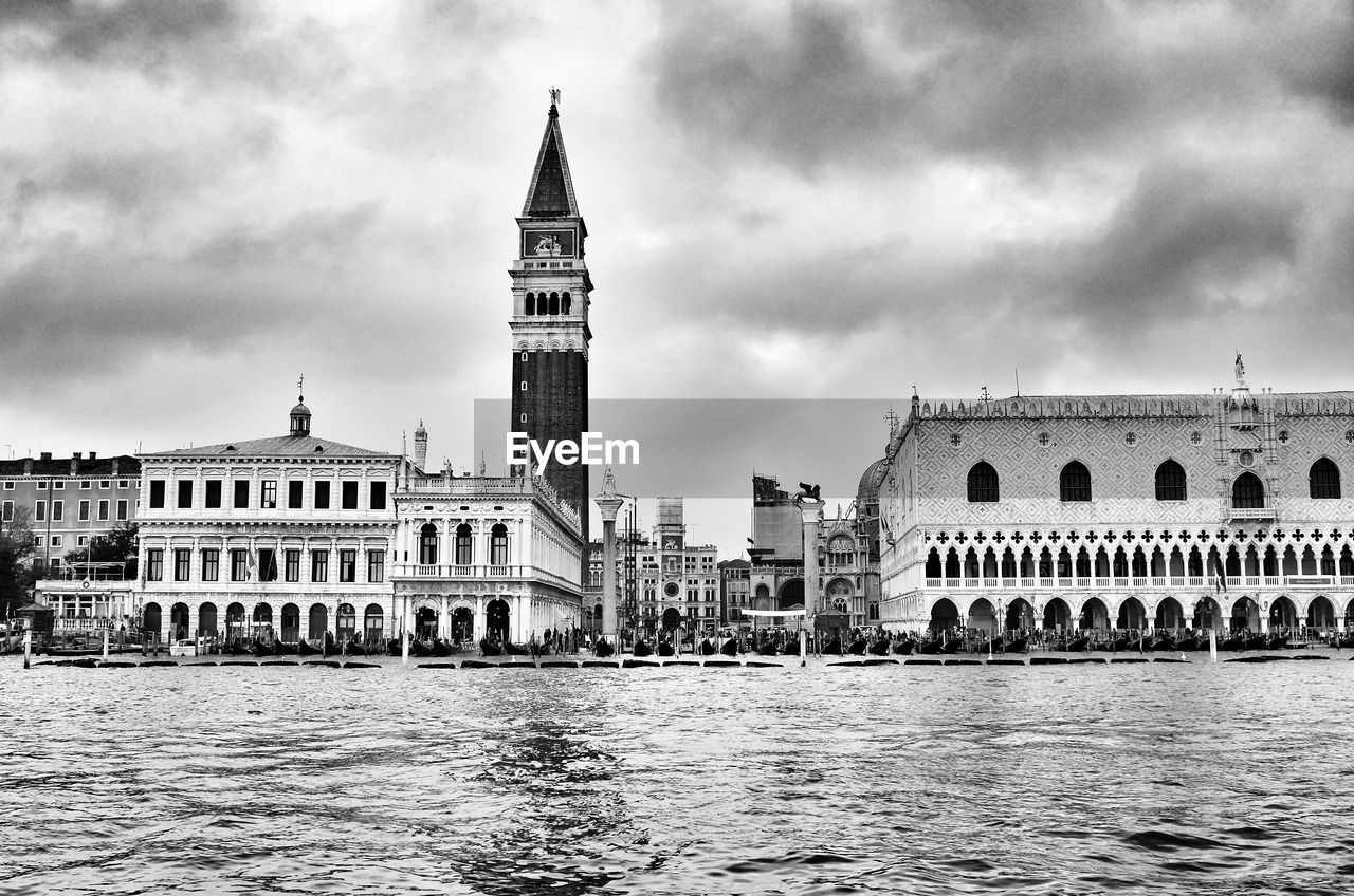 Grand canal by san marco campanile against cloudy sky
