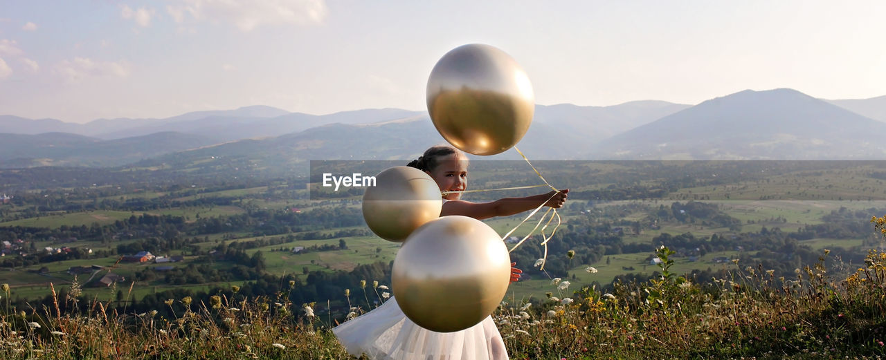 View of balloons on field against mountain range