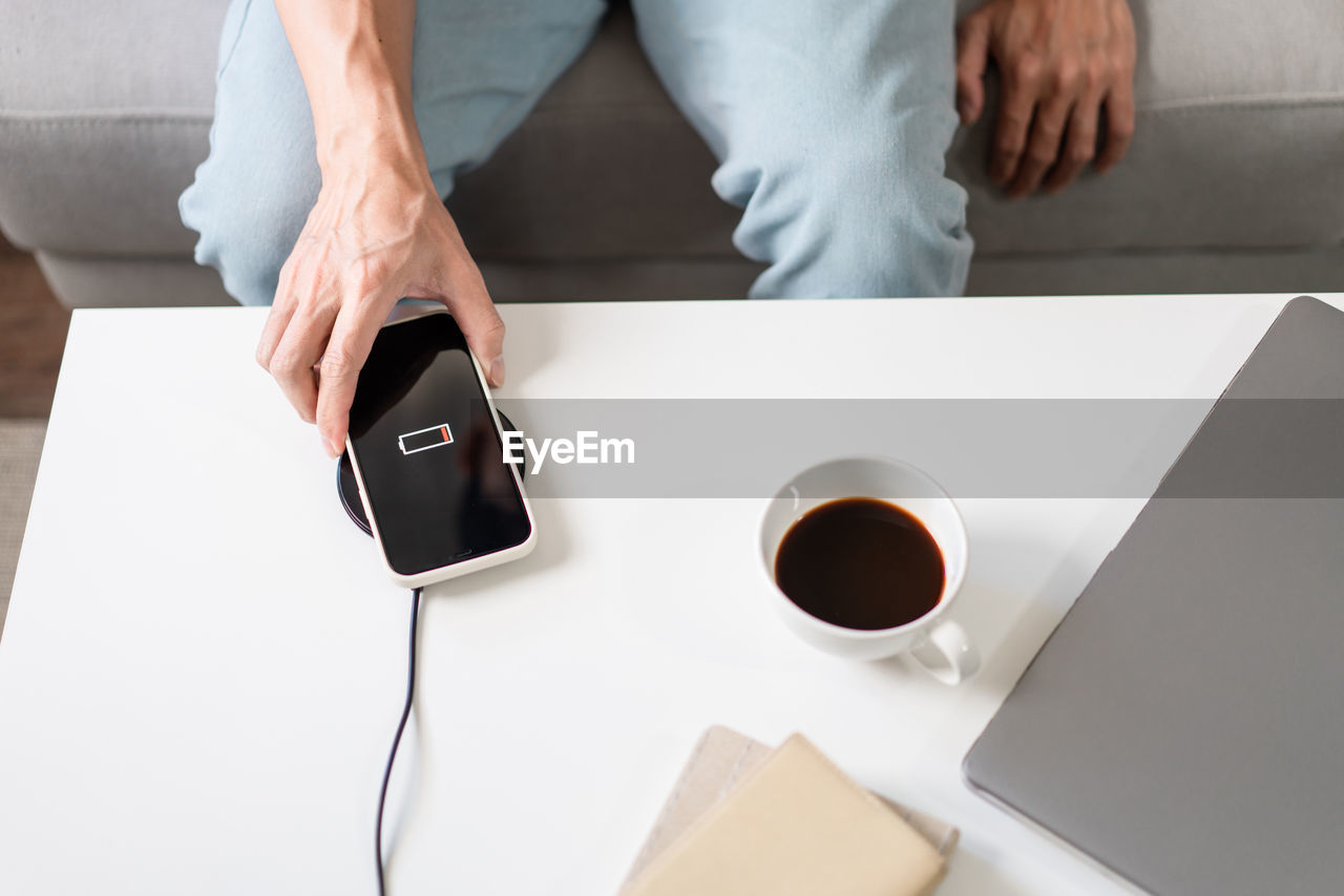 midsection of woman using mobile phone on table