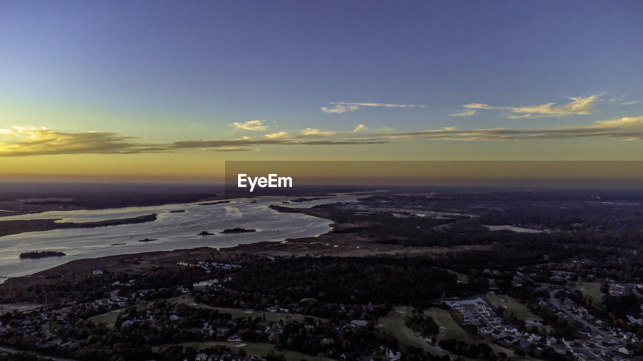 AERIAL VIEW OF SEA AND CITY AGAINST SKY DURING SUNSET