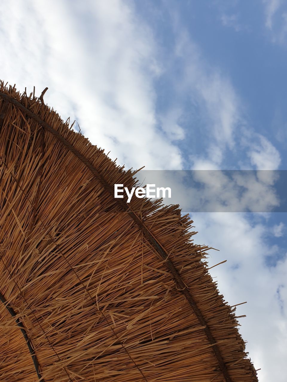 LOW ANGLE VIEW OF HAY BALES ON ROOF AGAINST SKY