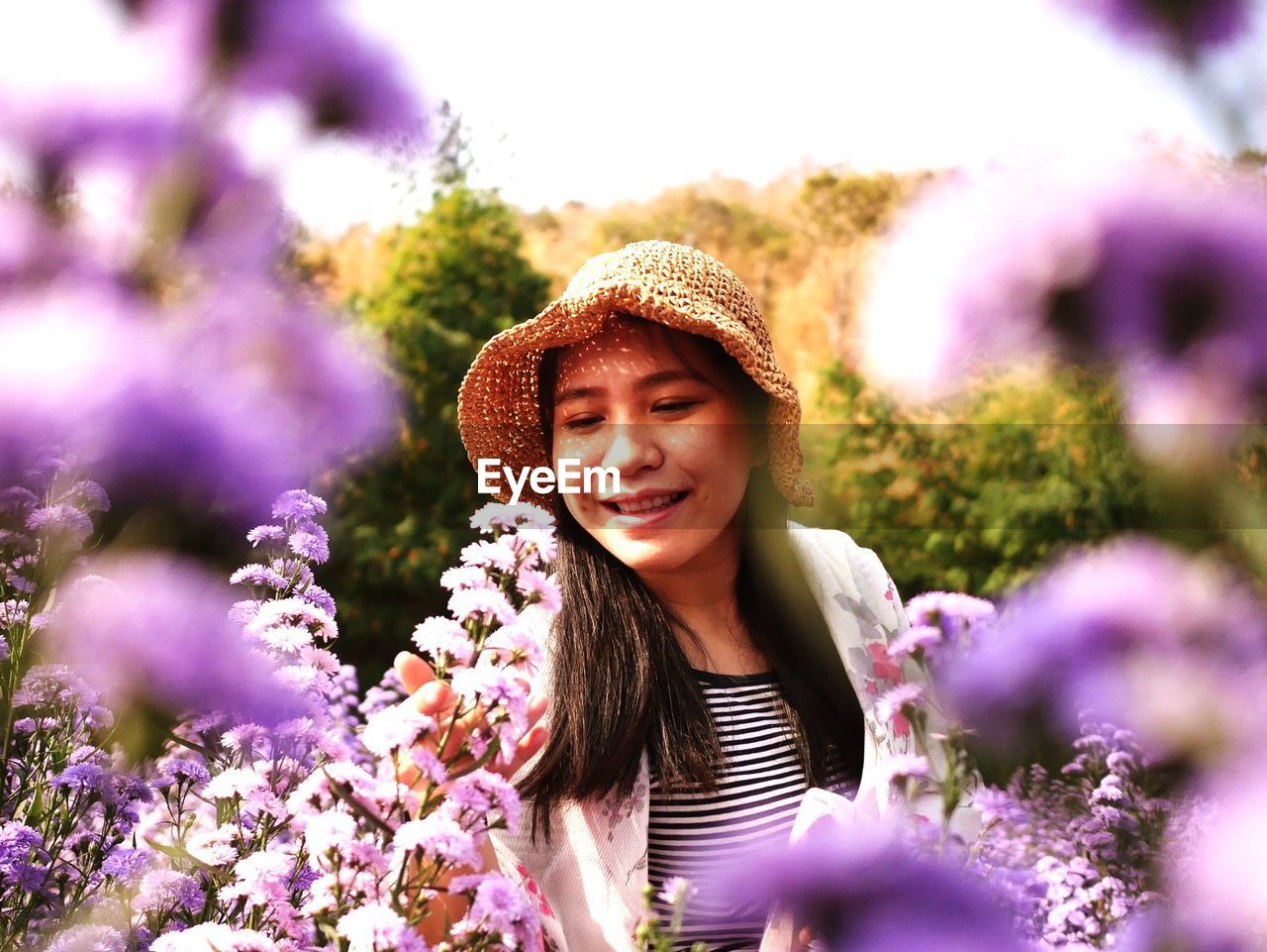 Portrait of smiling young woman against purple flowering plants