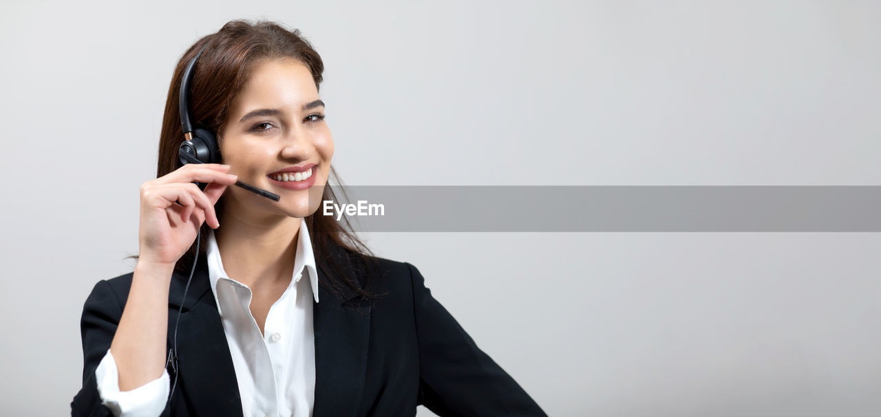 PORTRAIT OF A SMILING YOUNG WOMAN USING PHONE