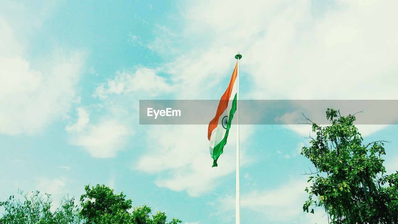 Low angle view of flag by trees