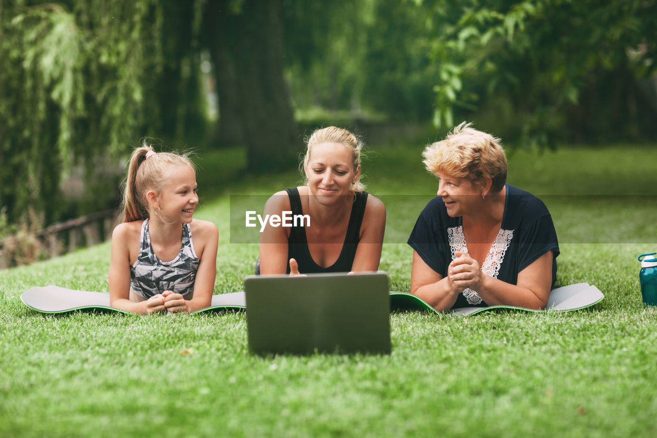 Multi generational family exercising with laptop on grass