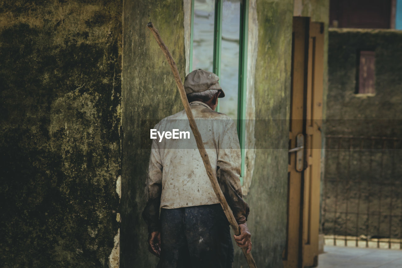 Rear view of man walking against wall