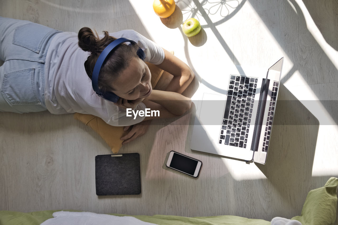 Young woman lying at the window at home with laptop