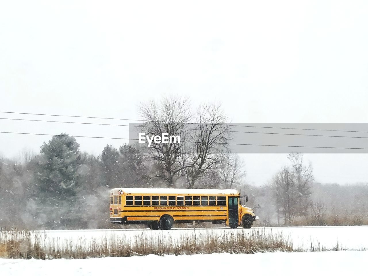 YELLOW CAR ON SNOW COVERED LANDSCAPE