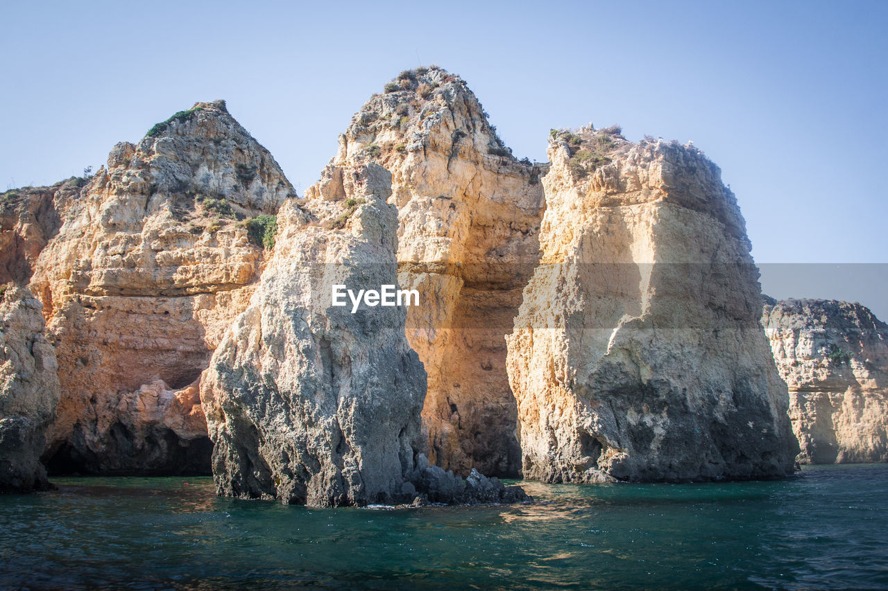Rock formations in sea against clear sky