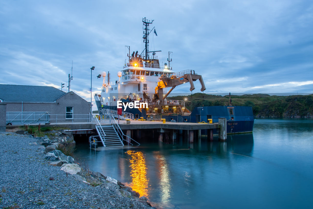 Commercial fishing boat in harbour. isle of skye, scotland. morning. lights reflected in the water.