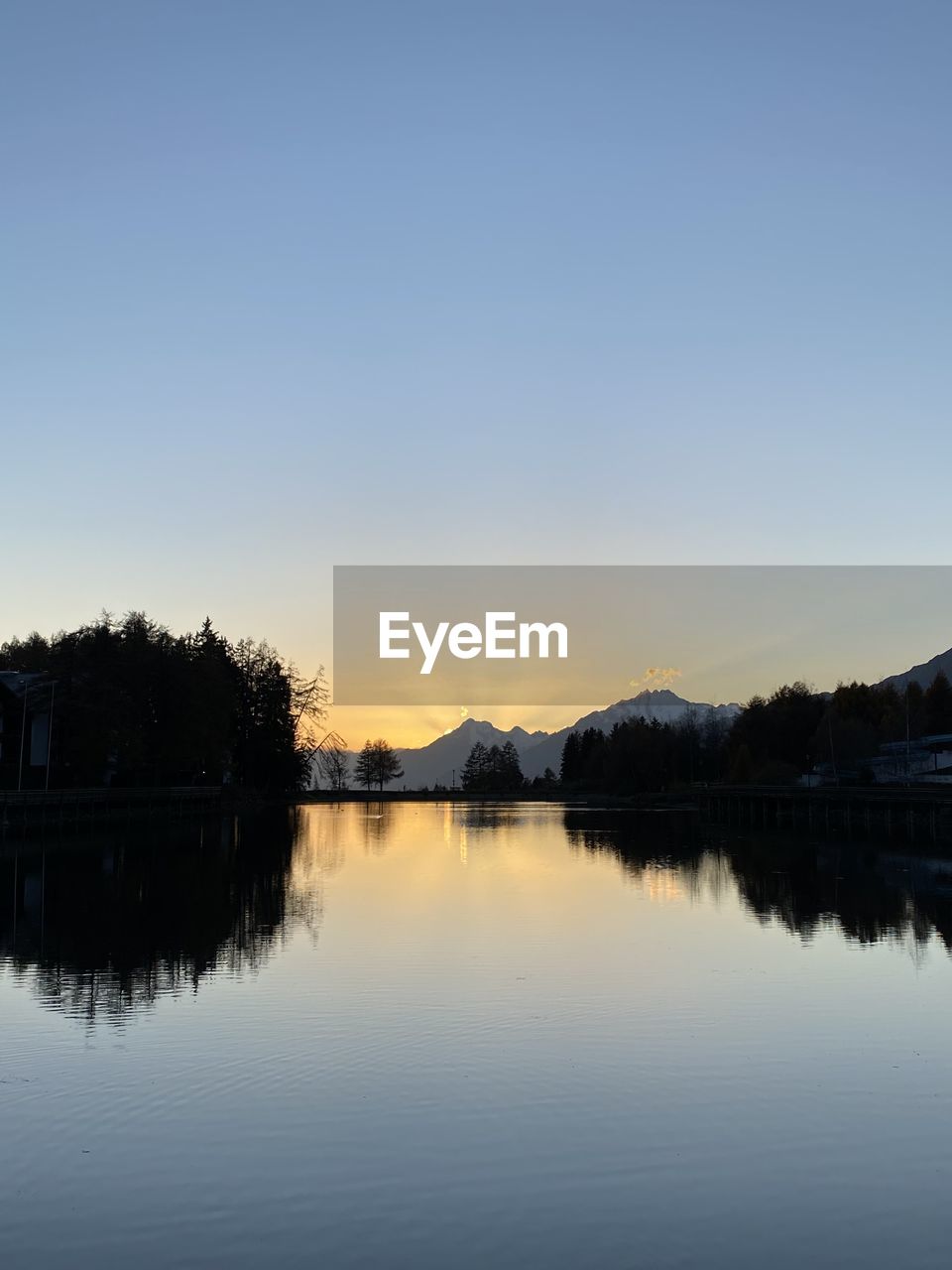SCENIC VIEW OF LAKE AGAINST CLEAR SKY AT SUNSET