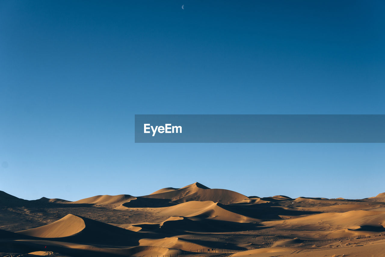 Scenic view of desert against clear blue sky