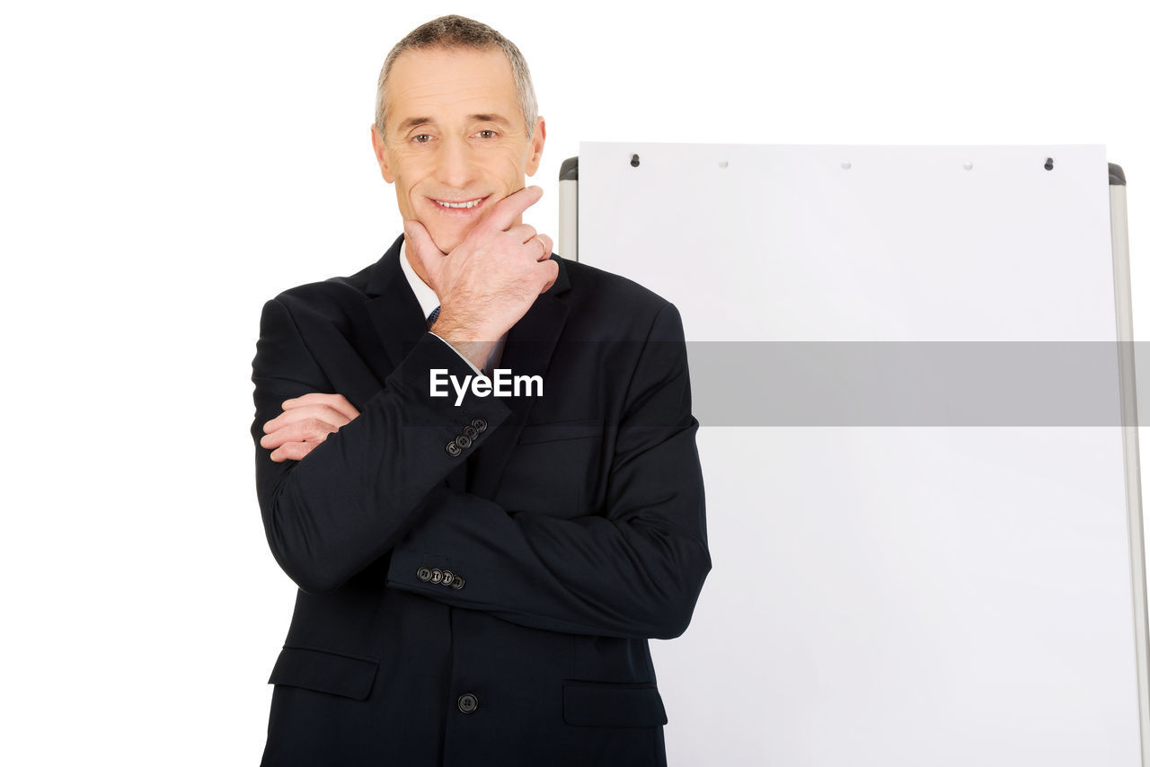 Portrait of businessman standing by whiteboard against white background