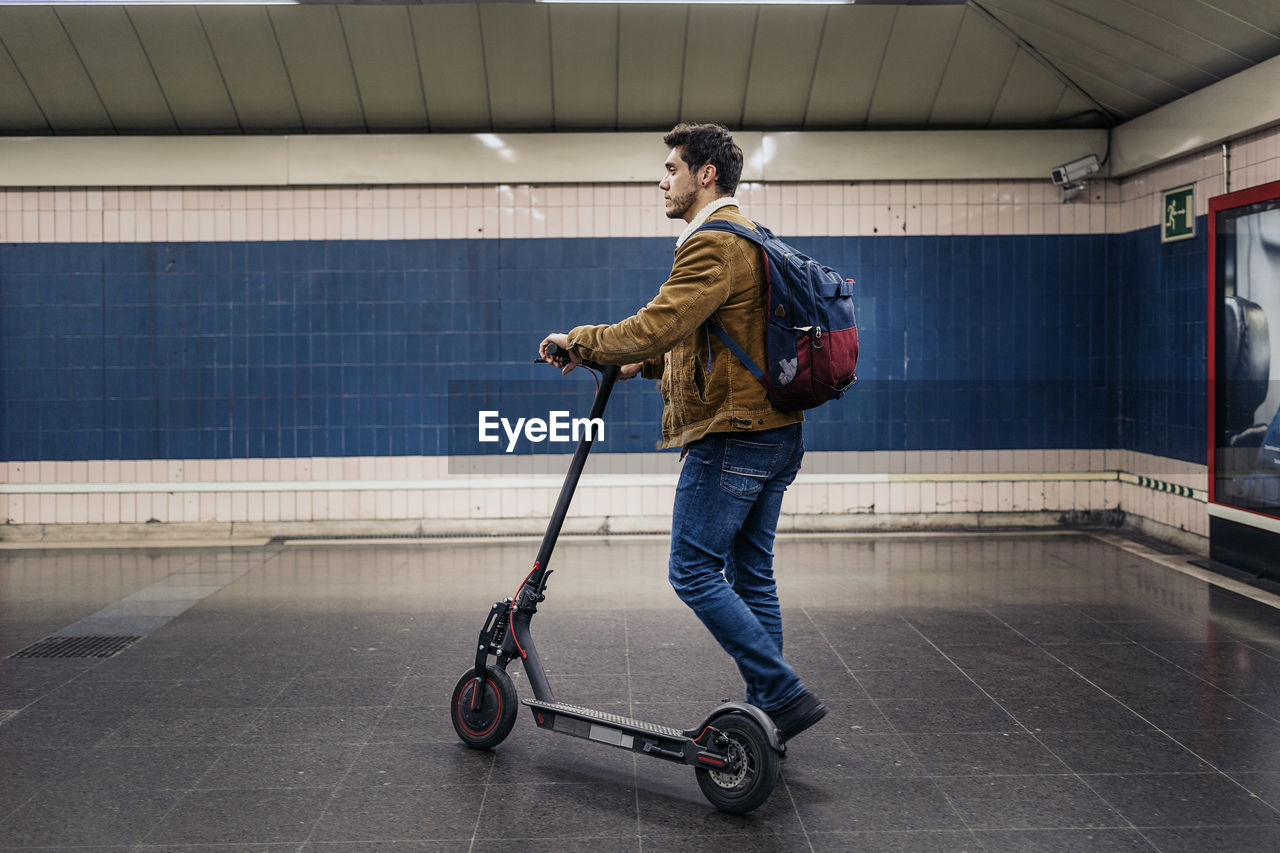 Full length of man with electric push scooter standing on subway station