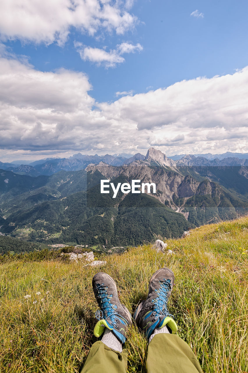 Low section of person on mountain against sky