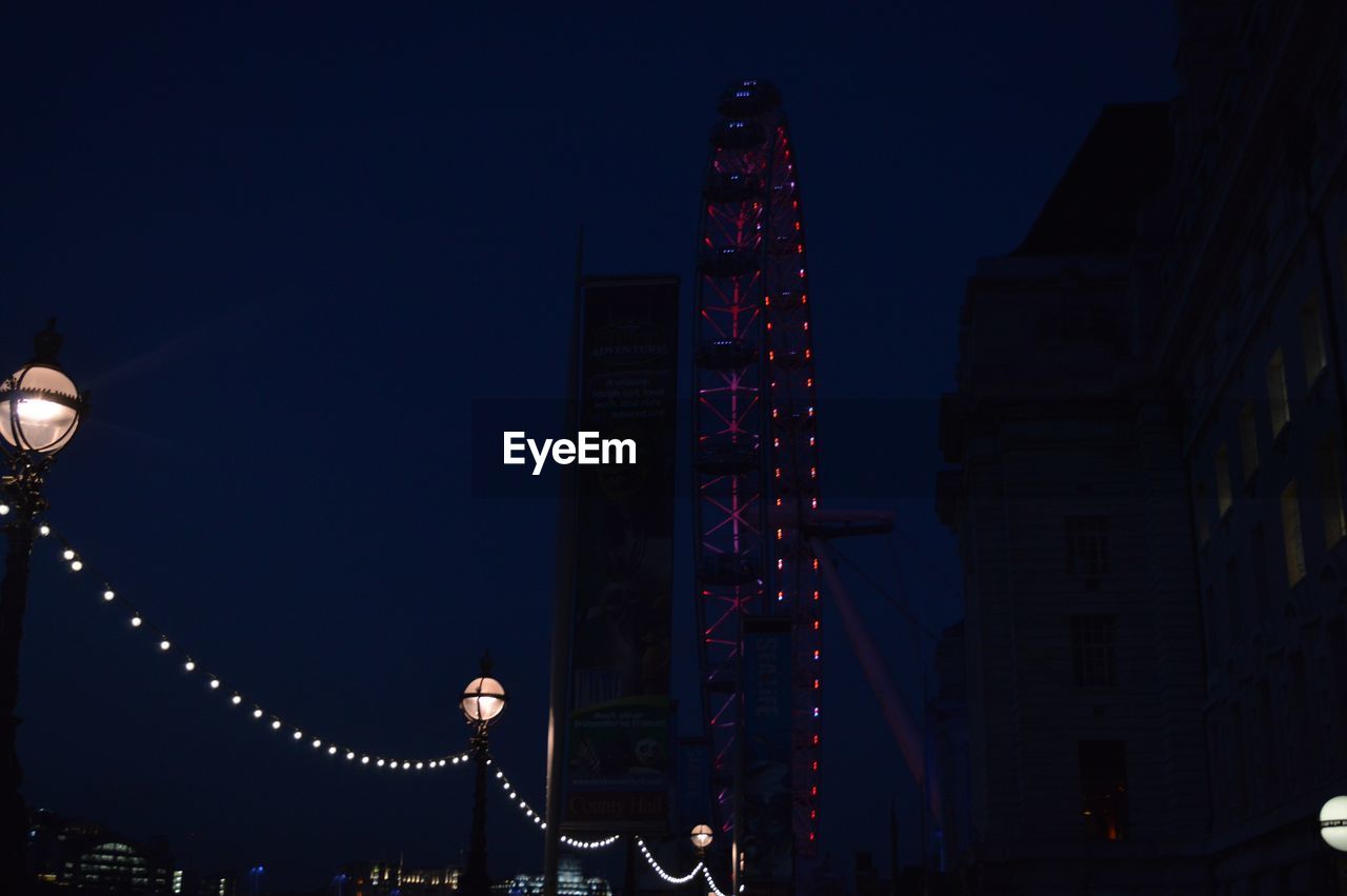 LOW ANGLE VIEW OF ILLUMINATED CHRISTMAS LIGHTS AGAINST SKY