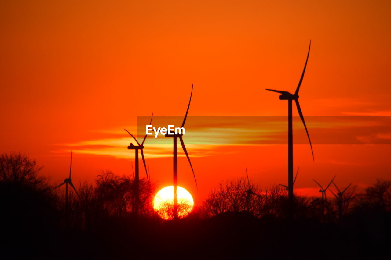 SILHOUETTE OF WIND TURBINES ON FIELD DURING SUNSET