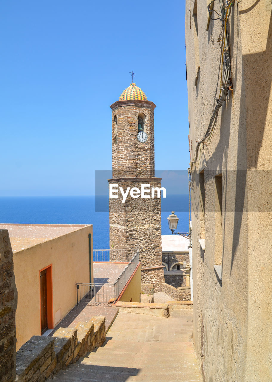 View of sea and buildings against clear blue sky