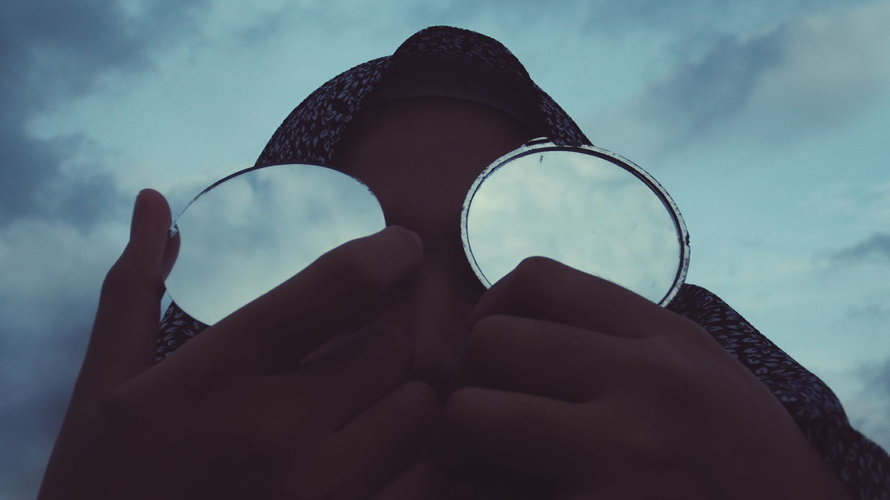 Close-up of person holding mirrors against sky during sunset