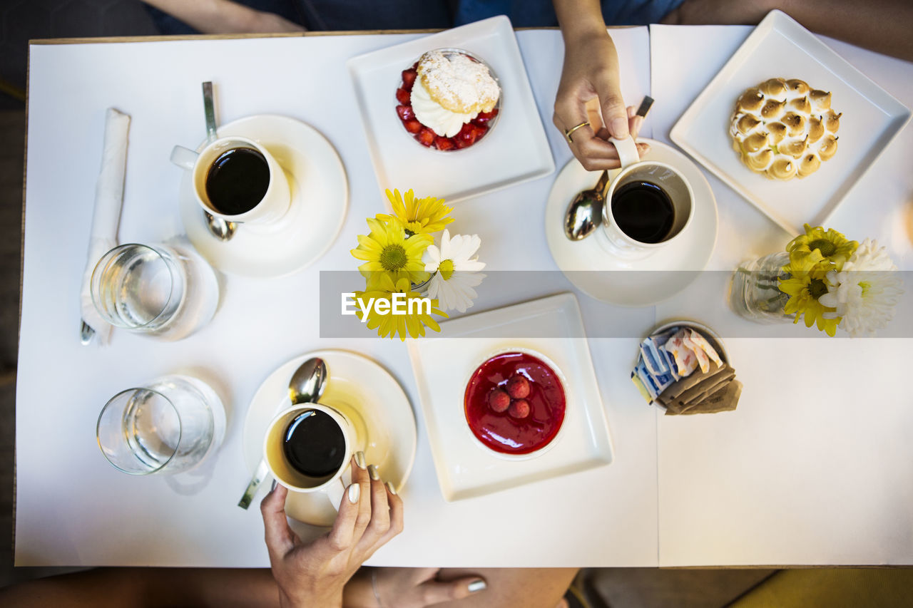 Cropped image of friends having coffee and dessert at table in restaurant