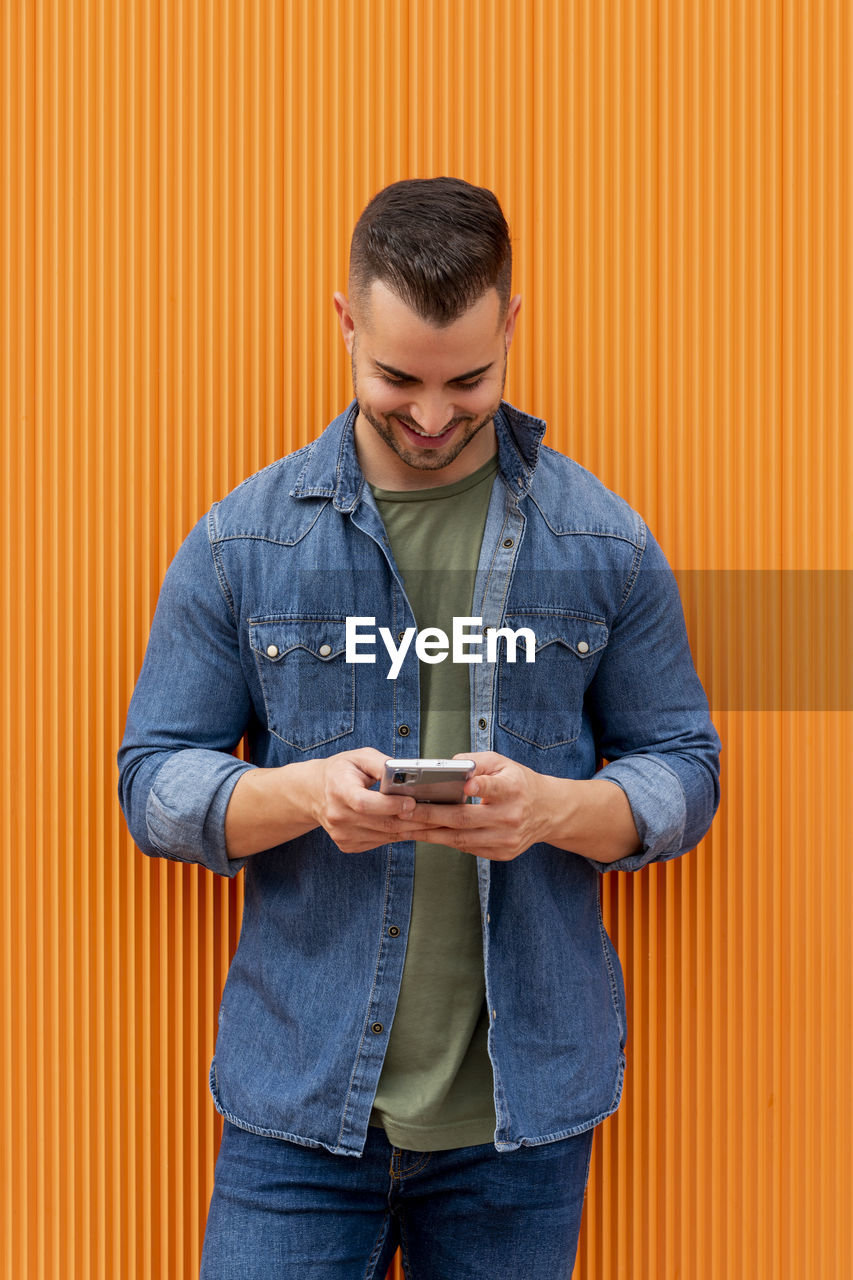 Portrait of a young cool man over orange background.