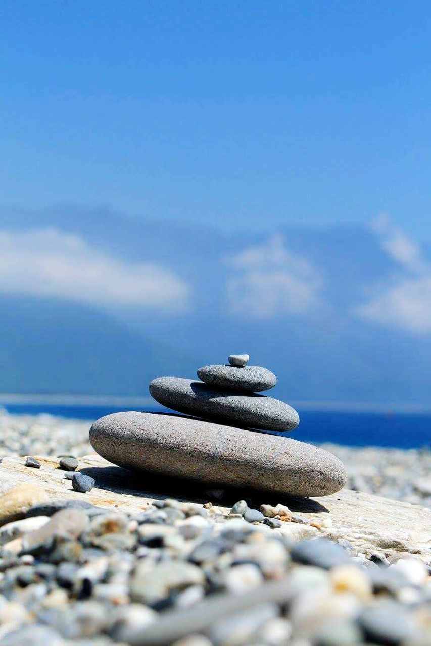 Stack of pebbles at beach against sky