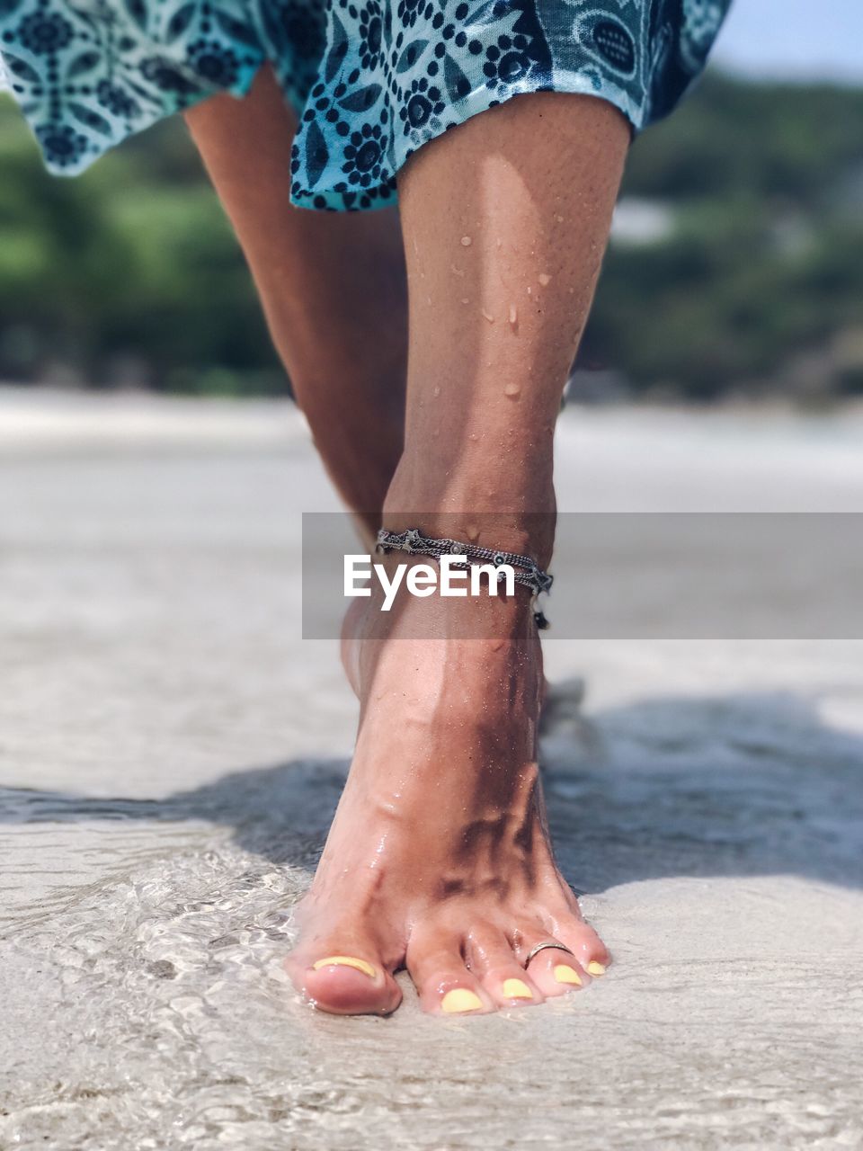 Low section of woman walking on shore at beach