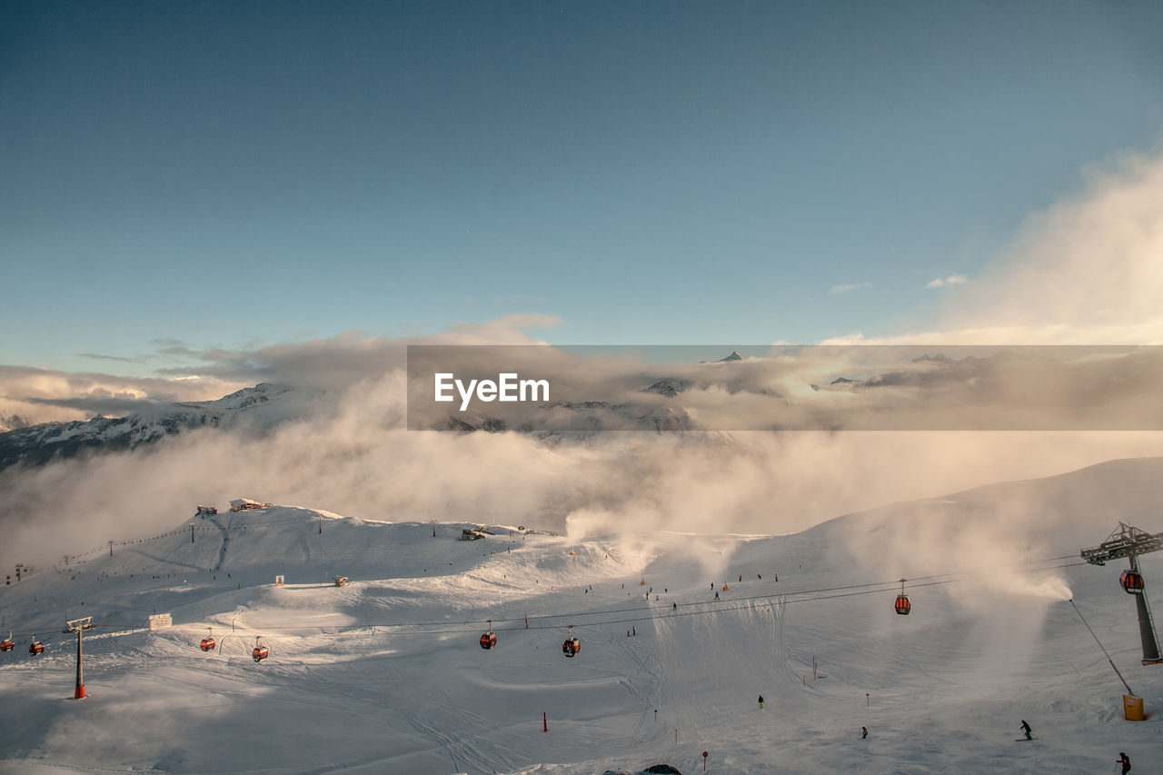 Scenic view of ski lift over snowcapped mountain against sky