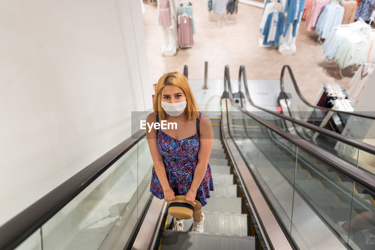 Portrait of young woman standing on escalator
