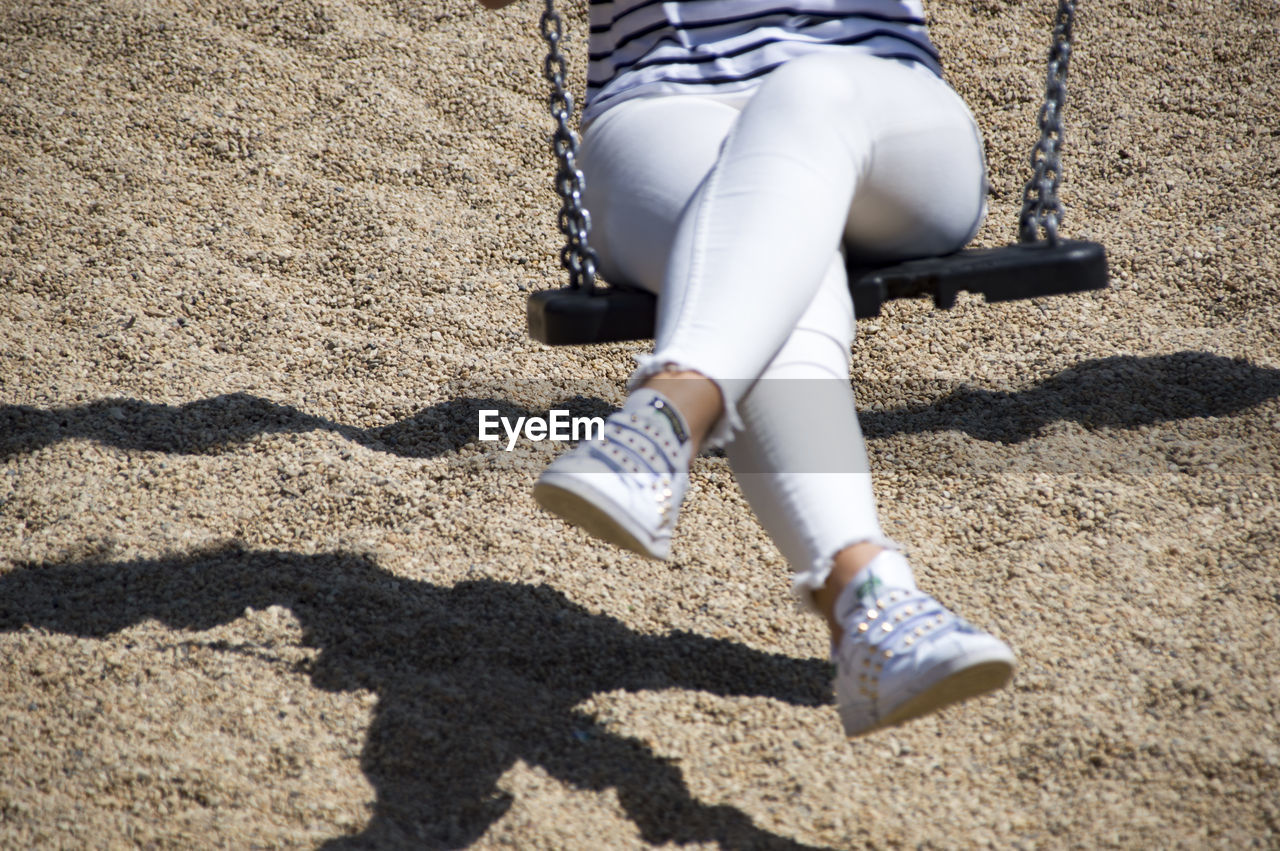 Low section of woman swinging at playground