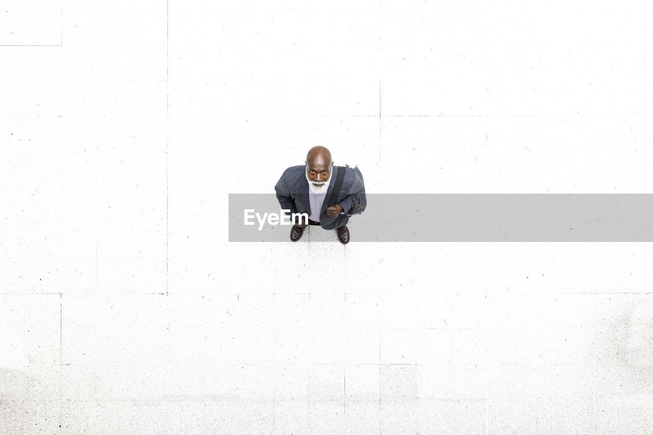 Senior businessman standing on white flooring at railroad station