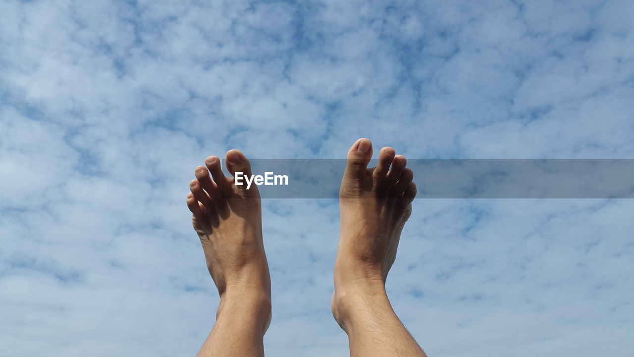 Low section of man against cloudy sky