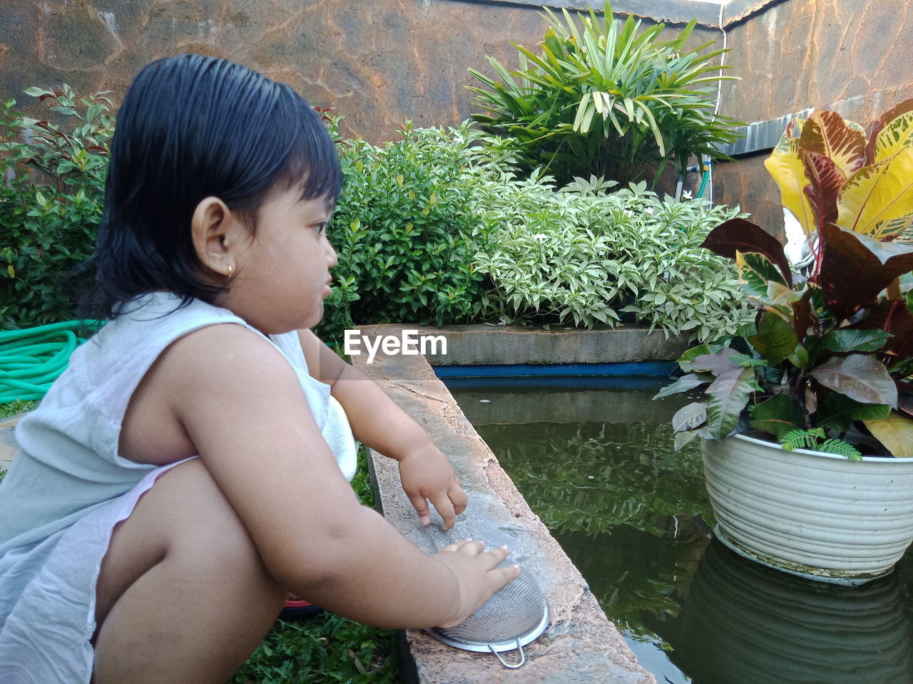 GIRL LOOKING AT POTTED PLANT IN BACKYARD