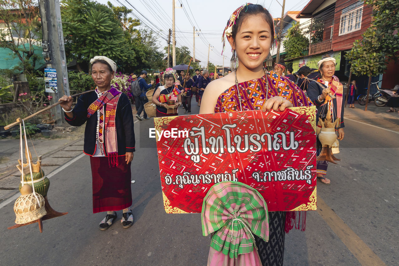 PORTRAIT OF SMILING WOMAN STANDING AGAINST THE STREET