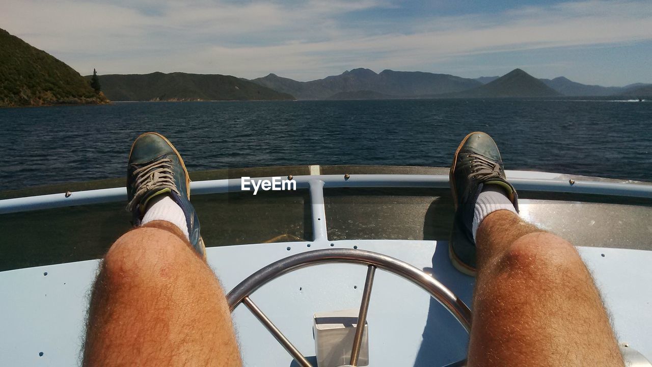 LOW SECTION OF MAN ON BOAT SAILING ON SEA