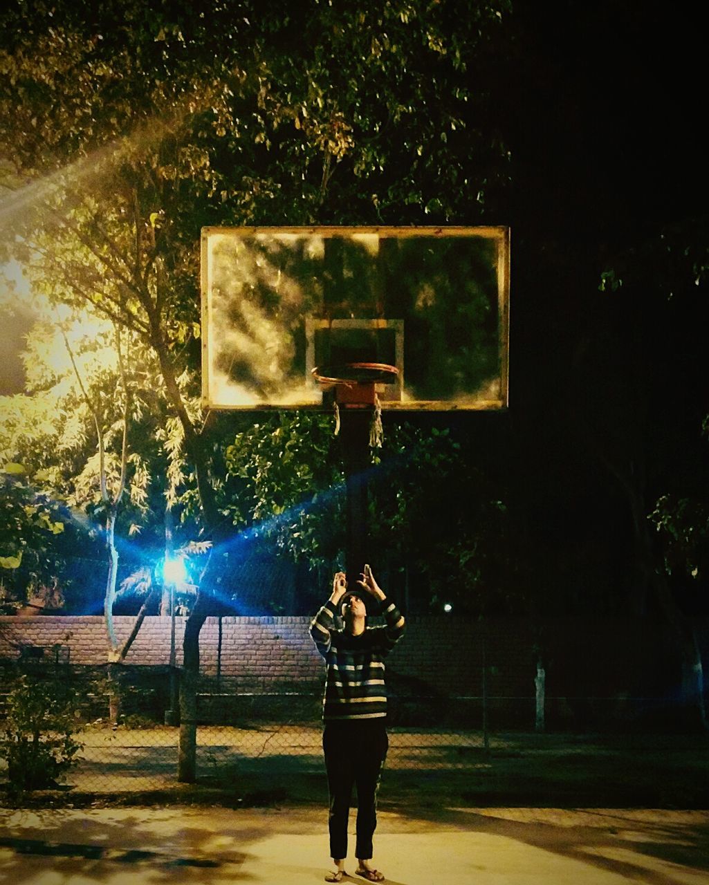 MAN PLAYING WITH BASKETBALL HOOP AGAINST COURT