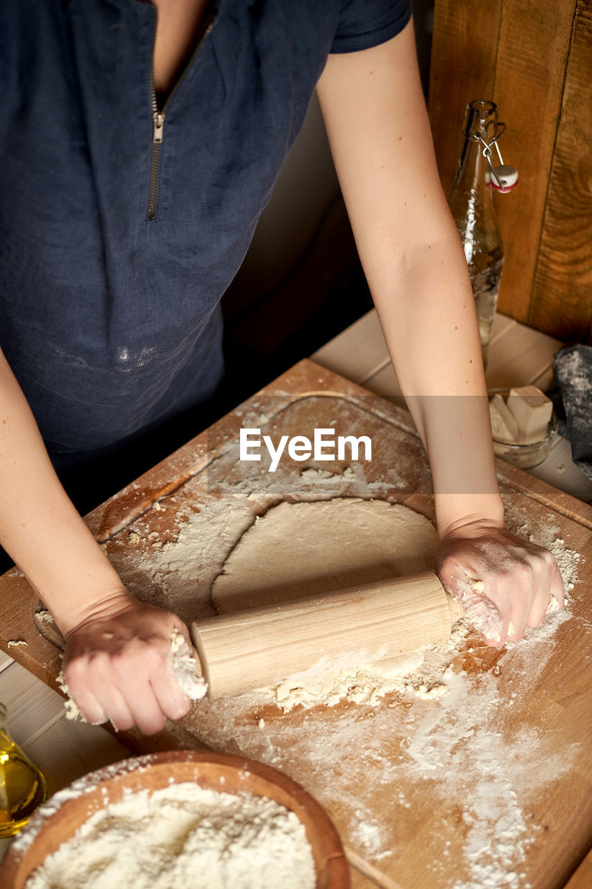 MIDSECTION OF WOMAN PREPARING FOOD AT TABLE