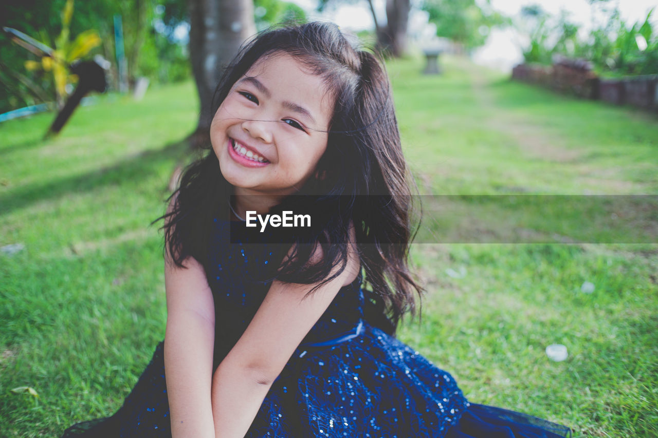 Portrait of smiling girl on grassy field at public park