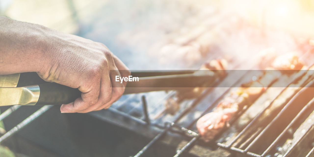 Cropped image of hand preparing barbecue