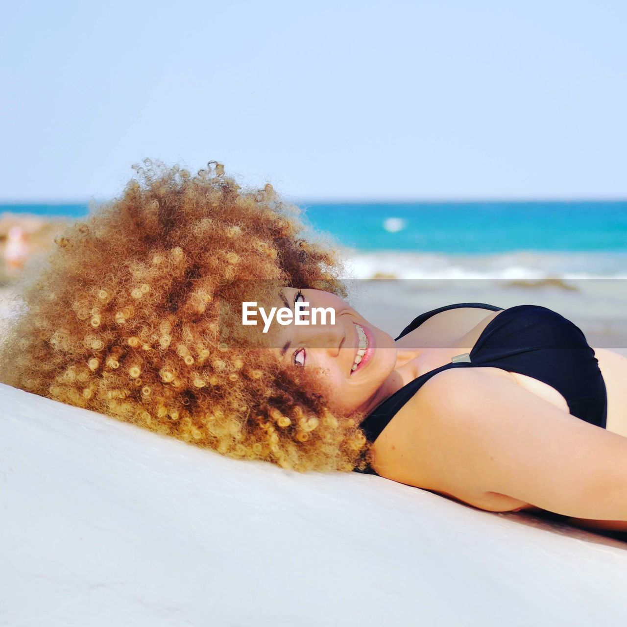 Portrait of smiling bikini woman lying at beach