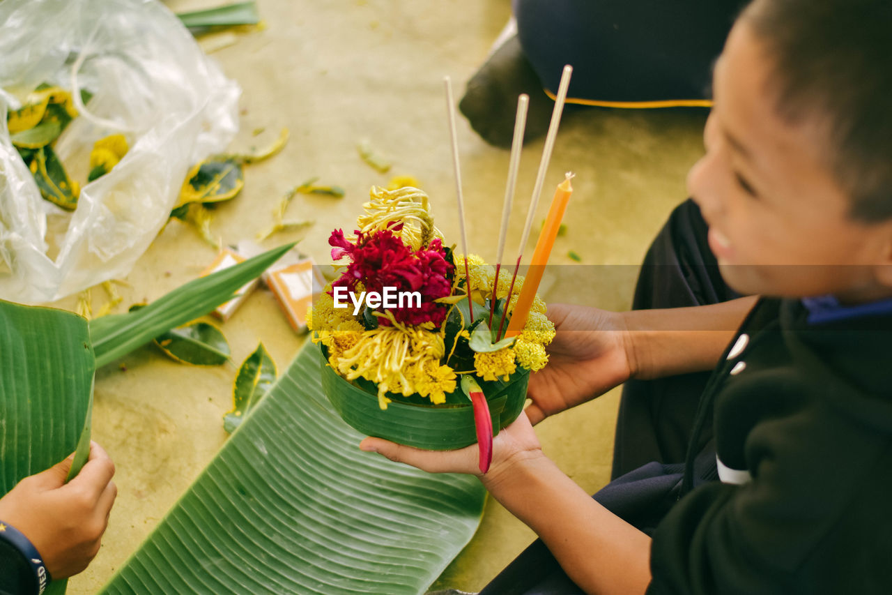 High angle view of smiling boy holding religious offering