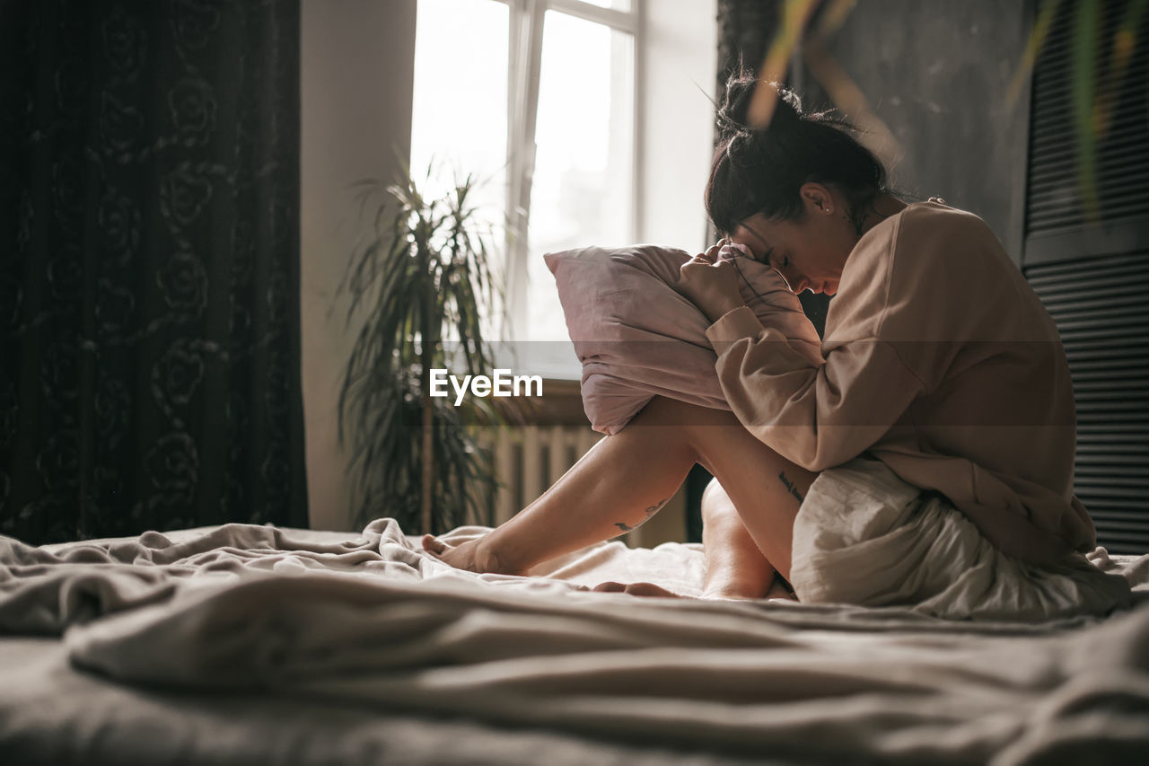 Woman sitting on bed at home