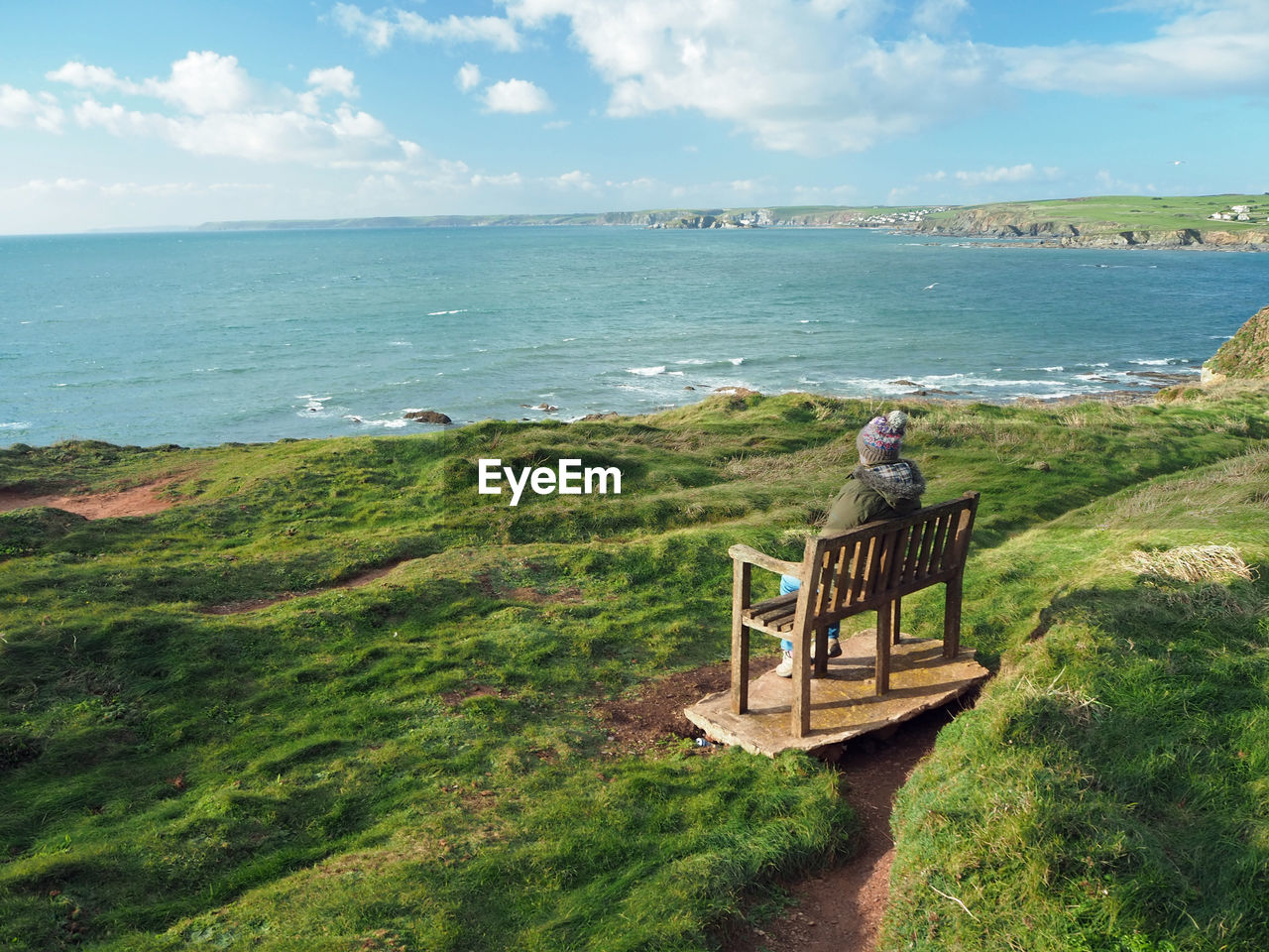 MAN STANDING BY RAILING AGAINST SEA