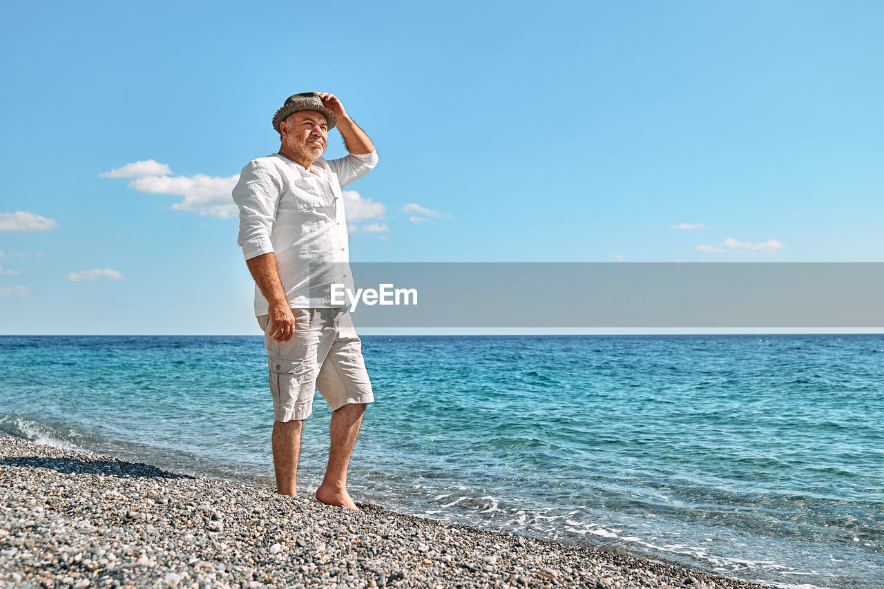 Happy middle-aged bearded man walking along beach. concept of leisure activities, wellness, freedom