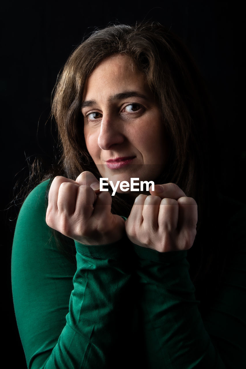 Portrait of smiling woman against black background