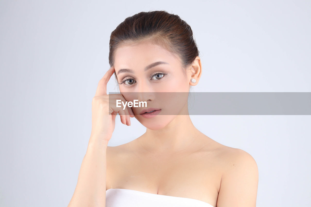 Portrait of shirtless young woman over white background