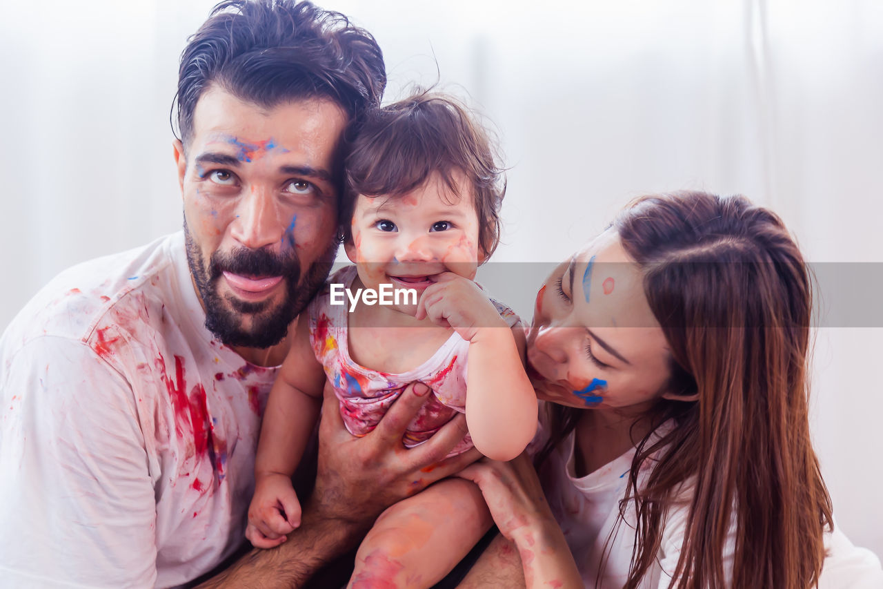 Portrait of mother father and little child or daughter with funny dirty colorful 