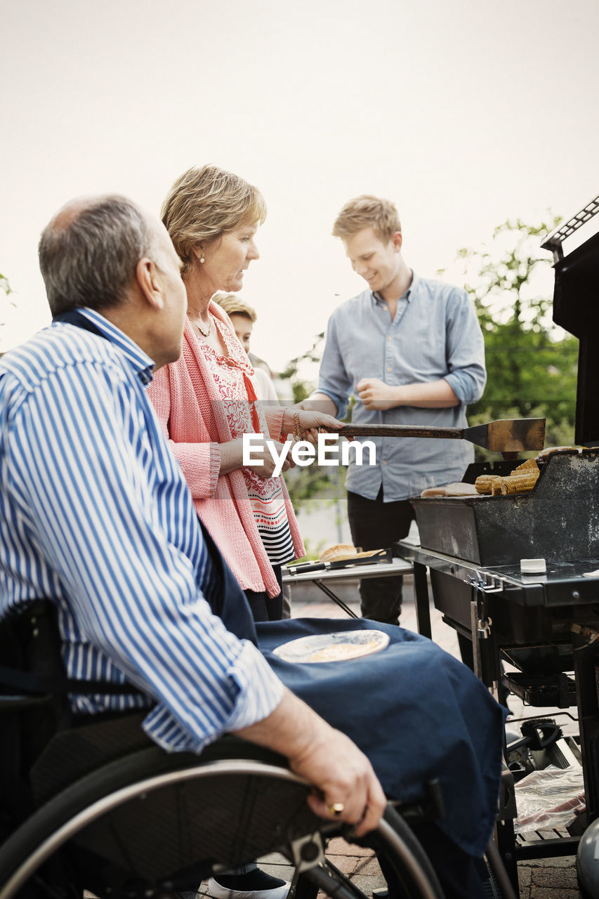 Grandparents with brothers barbecuing at yard